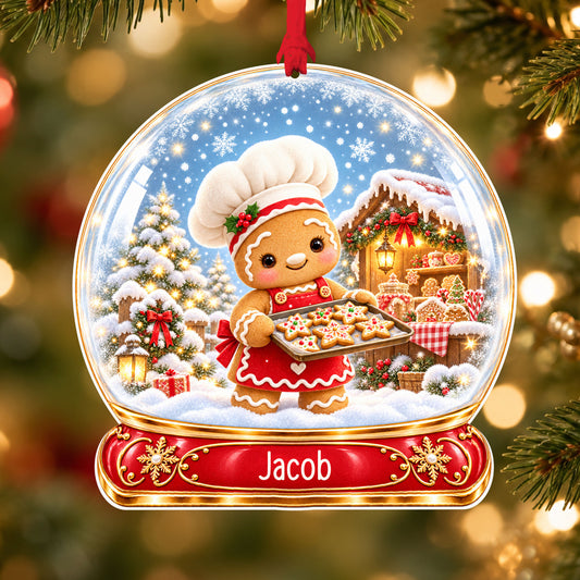 Personalised gingerbread baker acrylic snow globe Christmas bauble with custom name, hanging on a Christmas tree with red ribbon