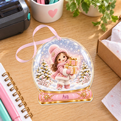 Personalised girl with presents snow globe bauble with name, white acrylic Christmas decoration with ribbon, shown on a desk