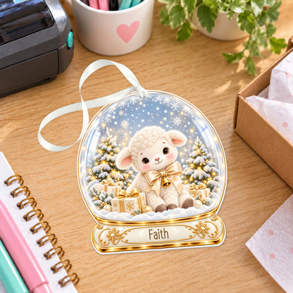Personalised ivory lamb snow globe bauble with name, white acrylic Christmas decoration with ribbon, shown on a desk