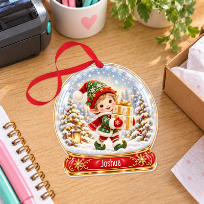 Personalised little elf with gifts snow globe bauble with name, white acrylic Christmas decoration with ribbon, shown on a desk
