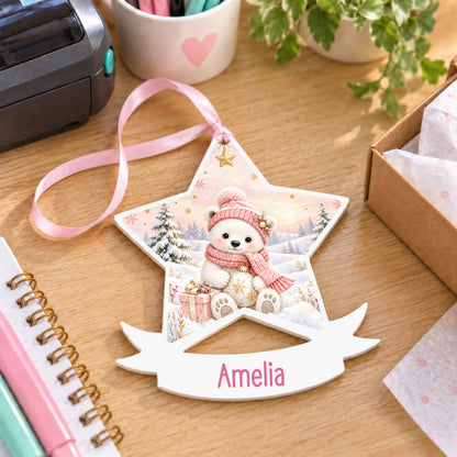 Personalised pink polar bear white acrylic star bauble with name, 10cm Christmas decoration with ribbon, shown on a desk