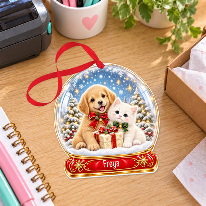 Personalised puppy and kitten snow globe bauble with name, white acrylic Christmas decoration with ribbon, shown on a desk