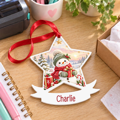 Personalised red and green snowman white acrylic star bauble with name, 10cm Christmas decoration with ribbon, shown on a desk