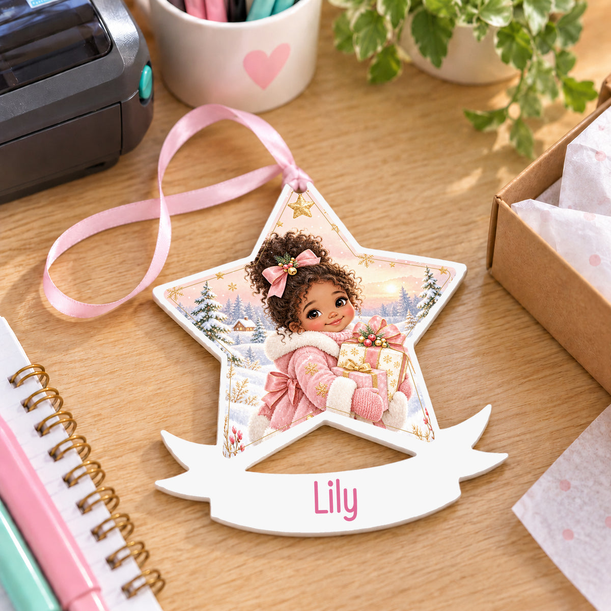 Personalised winter girl with gifts white acrylic star bauble with name, 10cm Christmas decoration with ribbon, shown on a desk