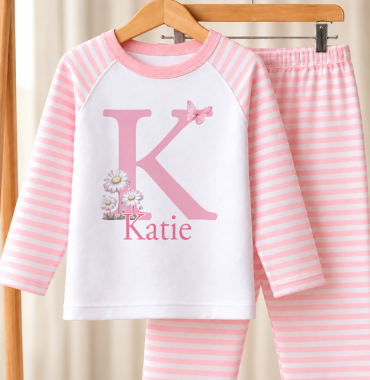 Personalised pink and white striped kids pyjamas with butterfly flower initial design and a custom name printed on the front