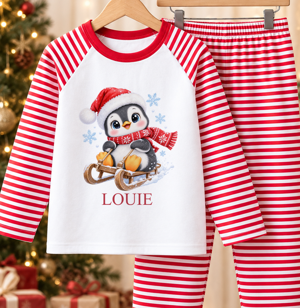 Personalised red and white striped kids Christmas pyjamas with Sledging Penguin design and a custom name printed on the front