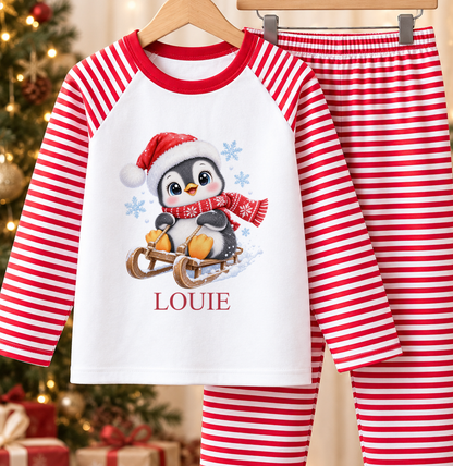 Personalised red and white striped kids Christmas pyjamas with Sledging Penguin design and a custom name printed on the front