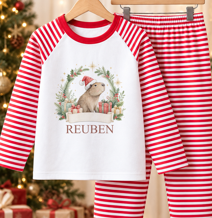 Personalised red and white striped kids Christmas pyjamas with Capybara Santa Wreath design and a custom name printed on the front