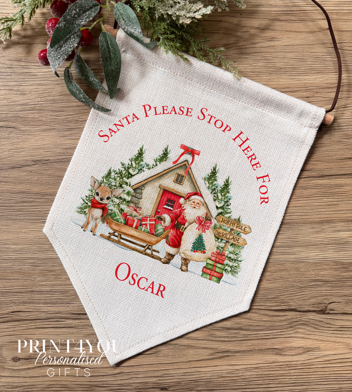 Linen wall banner personalised with a name, printed with Santa and his reindeer in a North Pole Christmas scene, hung from a wooden bar
