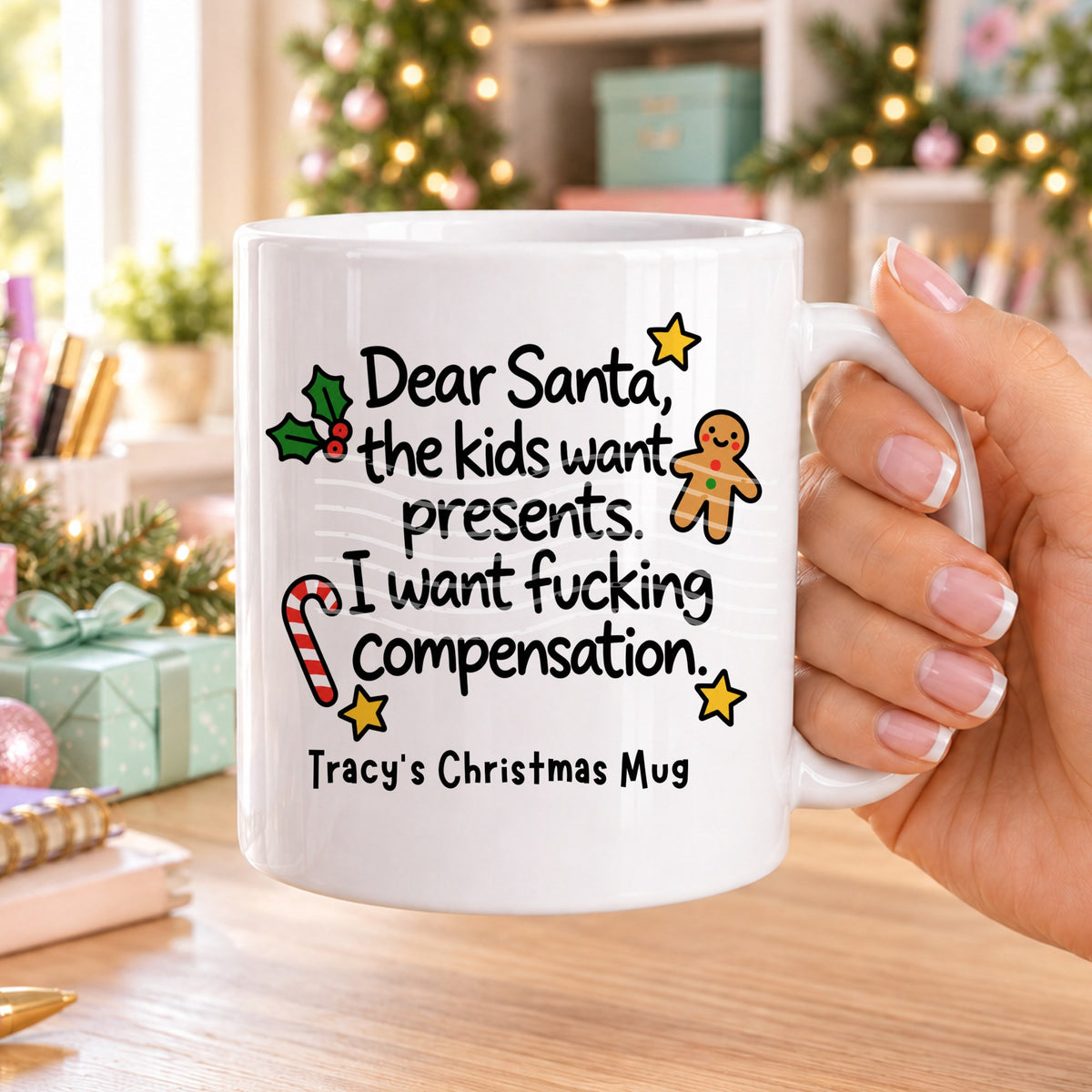 White personalised funny Christmas mug printed with “Dear Santa, the kids want presents. I want f*cking compensation.” with holly, a gingerbread man, candy cane and stars, and the line “Tracy’s Christmas Mug” underneath