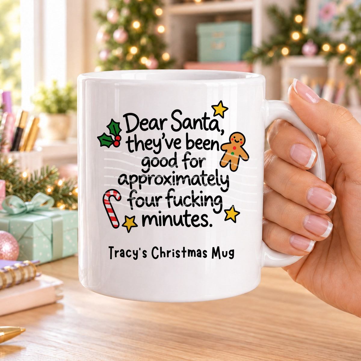 White personalised funny Christmas mug printed with “Dear Santa, they’ve been good for approximately four f*cking minutes.” with holly, a gingerbread man, candy cane and stars, and the line “Tracy’s Christmas Mug” underneath