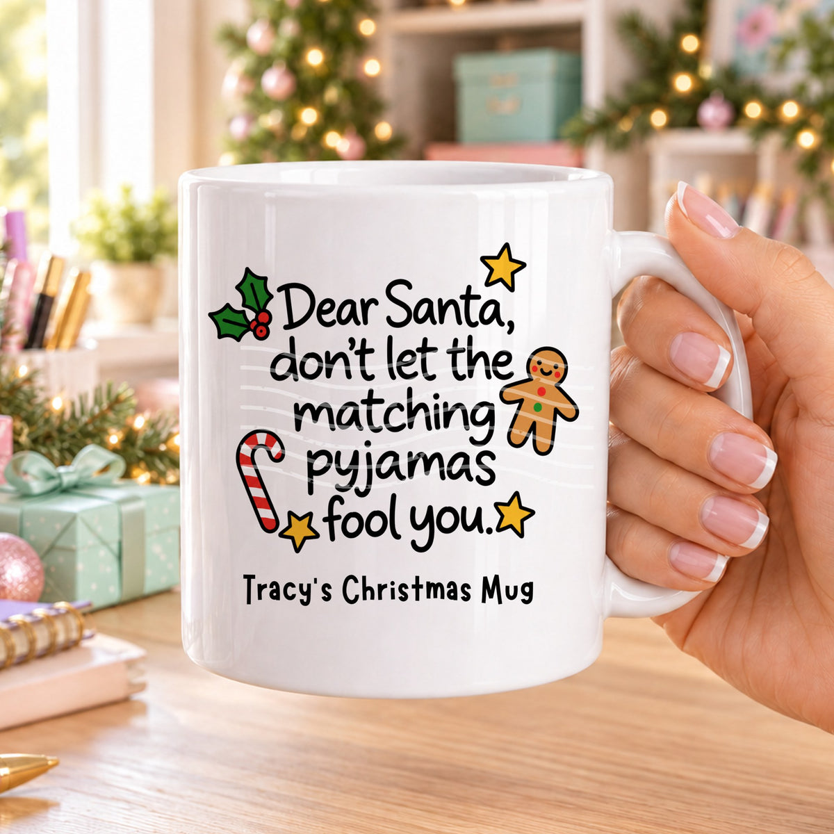 White personalised funny Christmas mug printed with “Dear Santa, don’t let the matching pyjamas fool you.” with holly, a gingerbread man, candy cane and stars, and the line “Tracy’s Christmas Mug” underneath