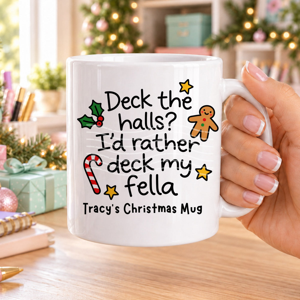 White personalised funny Christmas mug printed with “Deck the halls? I’d rather deck my fella” with holly, a gingerbread man, candy cane and stars, and the line “Tracy’s Christmas Mug” underneath