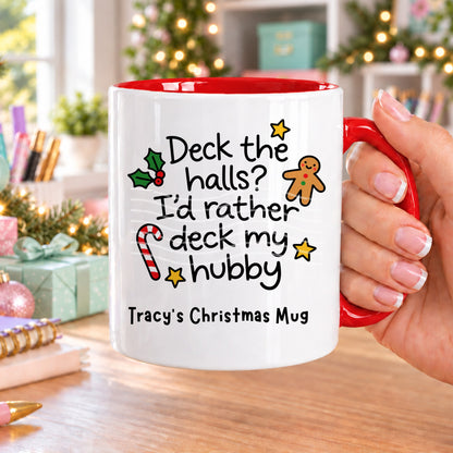 Red handled personalised funny Christmas mug printed with “Deck the halls? I’d rather deck my hubby” with holly, a gingerbread man, candy cane and stars, and the line “Tracy’s Christmas Mug” underneath