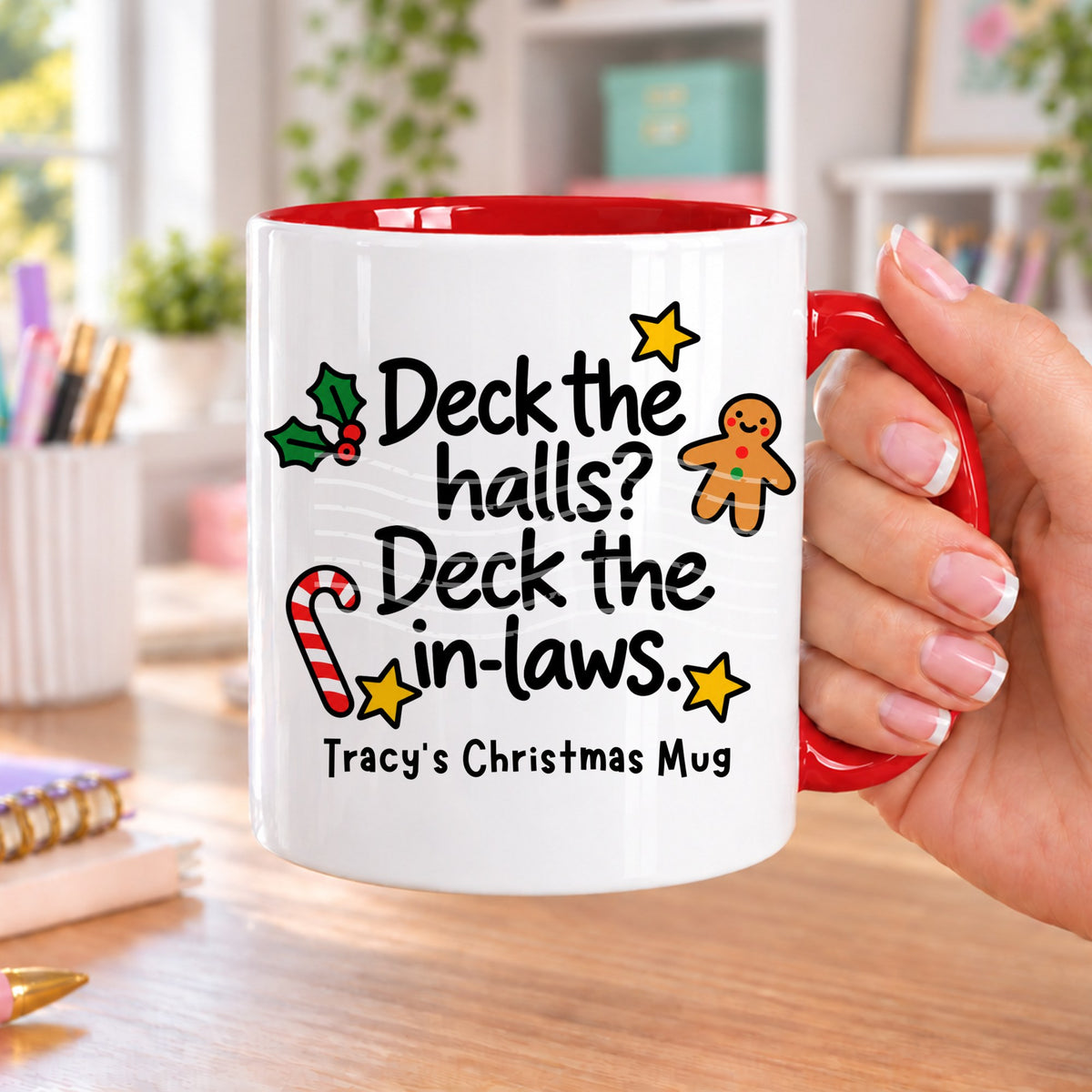Red handled personalised funny Christmas mug printed with “Deck the halls? Deck the in-laws.” with holly, a gingerbread man, candy cane and stars, and the line “Tracy’s Christmas Mug” underneath