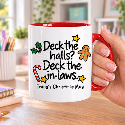 Red handled personalised funny Christmas mug printed with “Deck the halls? Deck the in-laws.” with holly, a gingerbread man, candy cane and stars, and the line “Tracy’s Christmas Mug” underneath