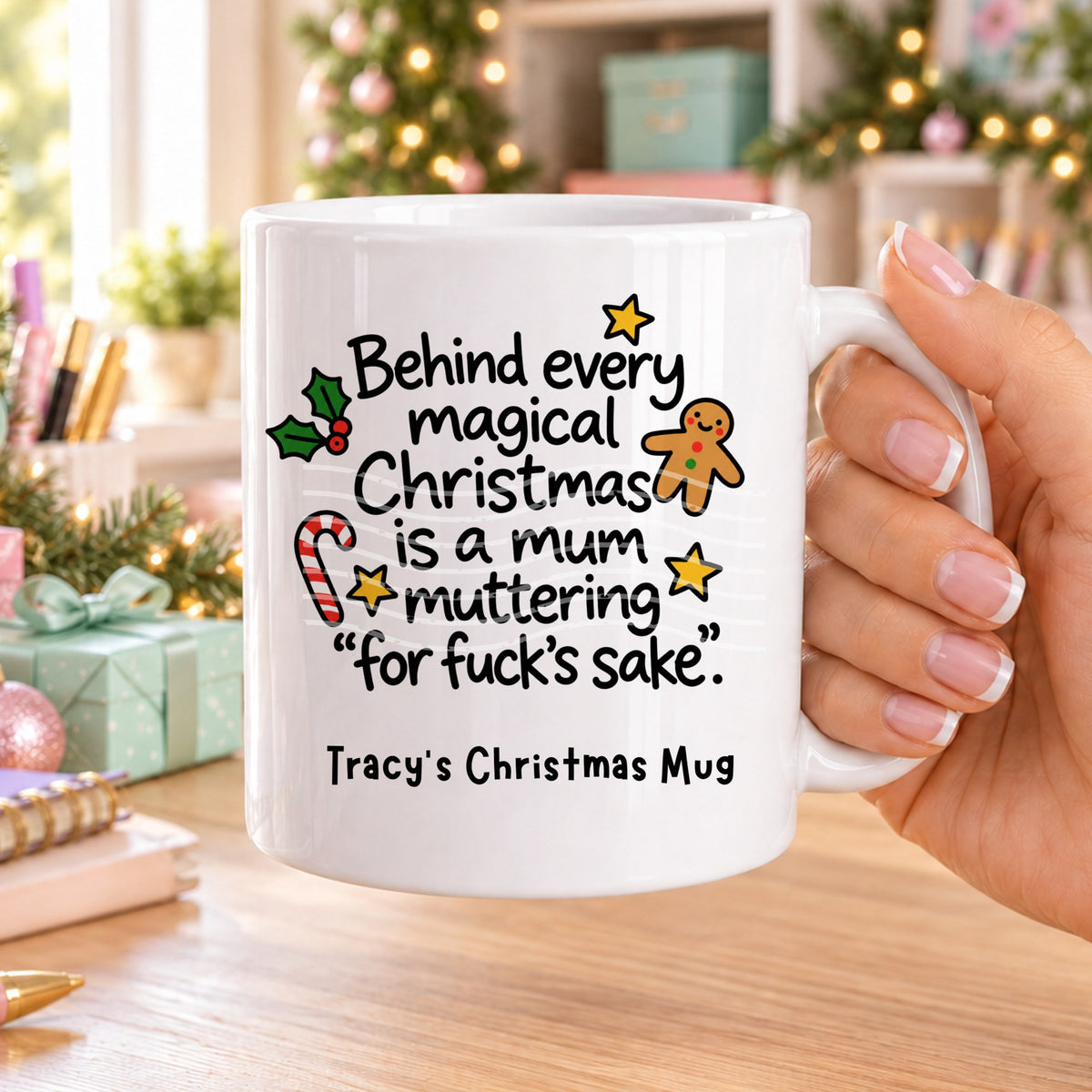 White personalised funny Christmas mug printed with “Behind every magical Christmas is a mum muttering ‘for f*ck’s sake’.” with holly, a gingerbread man, candy cane and stars, and the line “Tracy’s Christmas Mug” underneath
