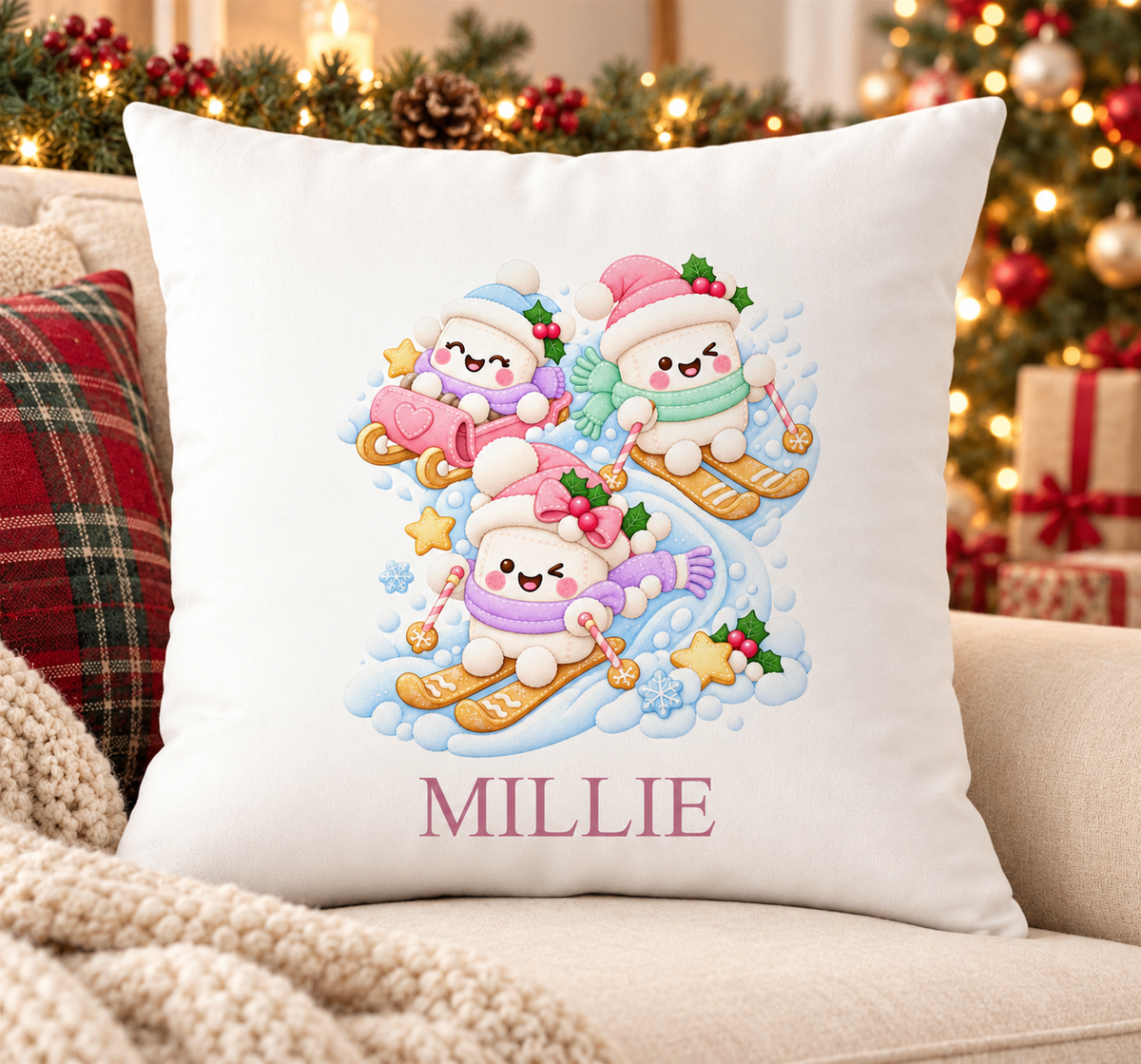 Personalised white Christmas cushion with three marshmallows skiing in bobble hats and a name printed underneath, on a festive sofa