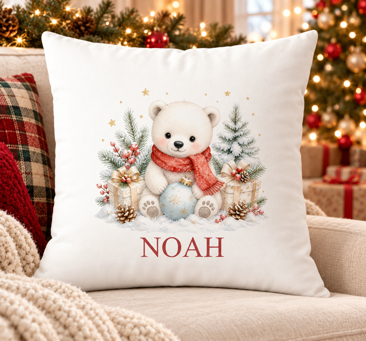 Personalised white Christmas cushion with a fluffy polar bear in a red scarf with pine and baubles and a name printed underneath, on a festive sofa