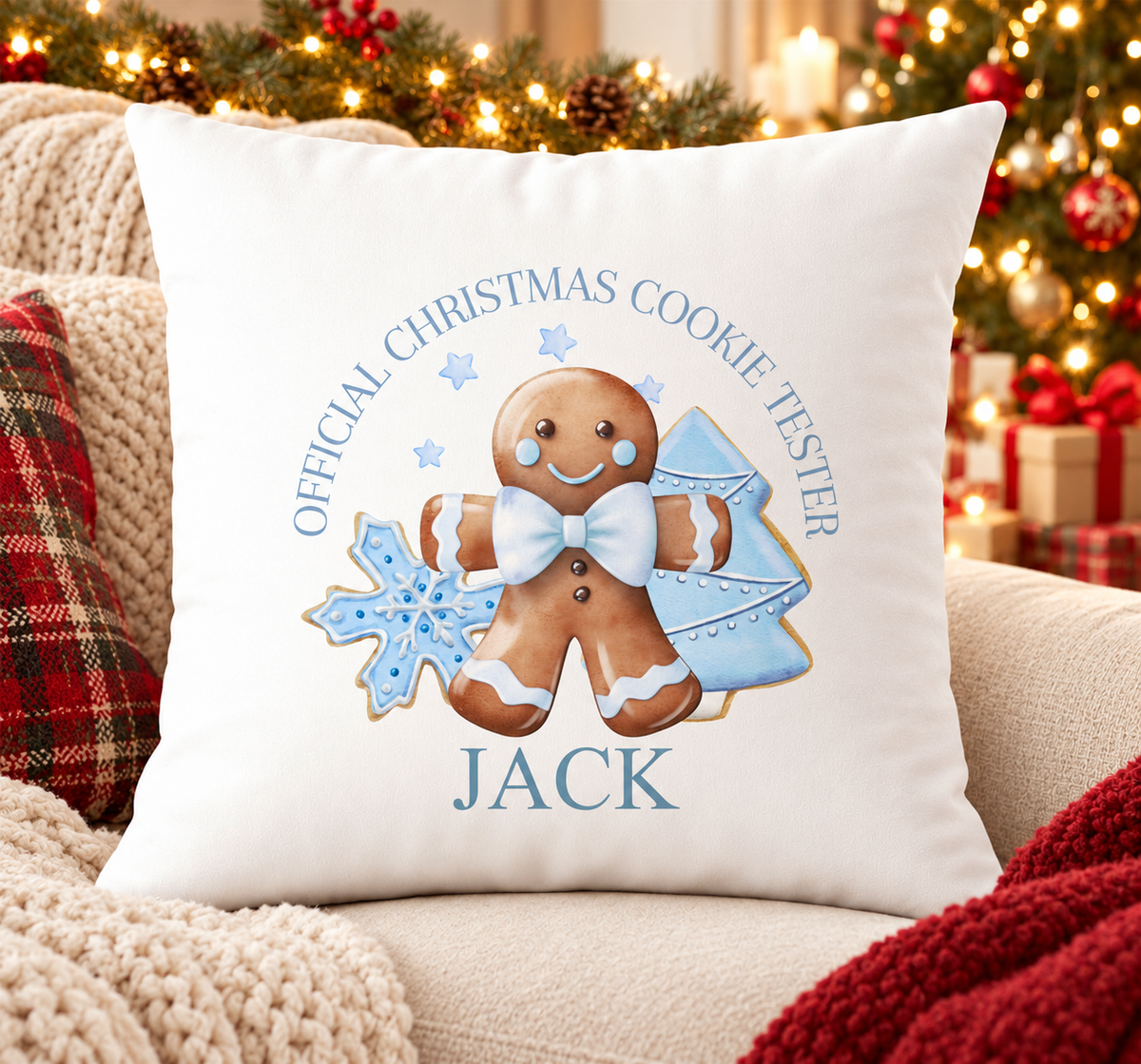 Personalised white Christmas cushion with an 'Official Christmas Cookie Tester' gingerbread design in blue and a name printed underneath, on a festive sofa