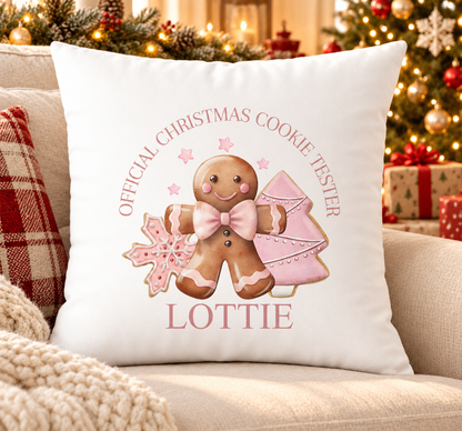 Personalised white Christmas cushion with an 'Official Christmas Cookie Tester' gingerbread design in pink and a name printed underneath, on a festive sofa