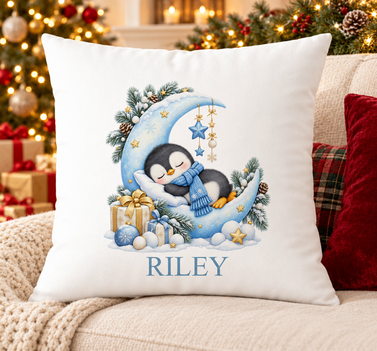Personalised white Christmas cushion with a sleepy penguin on a crescent moon and a name printed underneath, on a festive sofa
