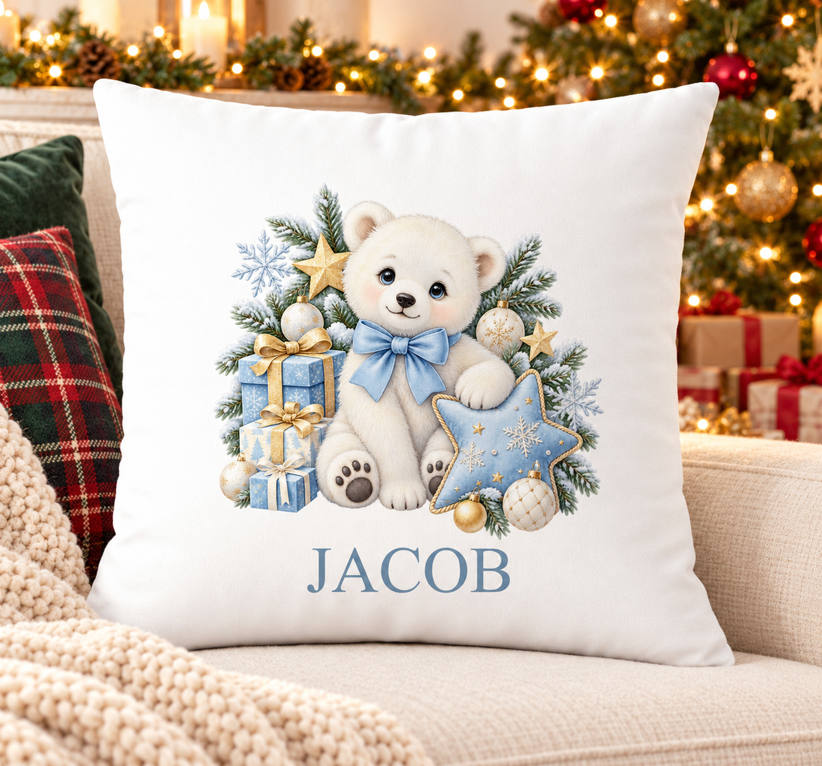 Personalised white Christmas cushion with a polar bear with a blue bow, presents and a star and a name printed underneath, on a festive sofa