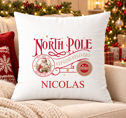 Personalised white Christmas cushion with a red 'North Pole Express Delivery' design with a Nice List stamp and a name printed underneath, on a festive sofa