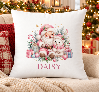 Personalised white Christmas cushion with a pink Santa hugging a polar bear cub and a name printed underneath, on a festive sofa