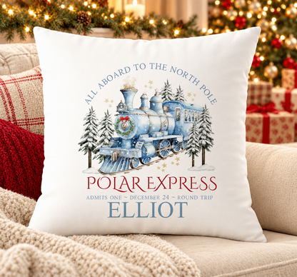 Personalised white Christmas cushion with a blue steam train travelling to the North Pole and a name printed underneath, on a festive sofa