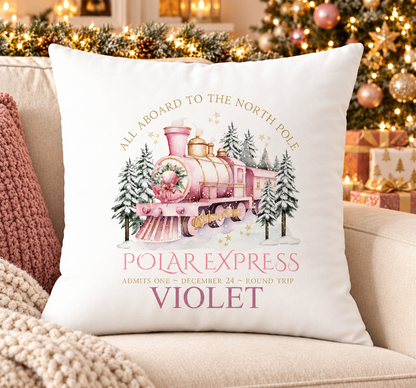 Personalised white Christmas cushion with a pink steam train travelling to the North Pole and a name printed underneath, on a festive sofa