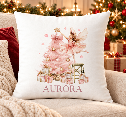 Personalised white Christmas cushion with a sugar plum fairy decorating a pink Christmas tree and a name printed underneath, on a festive sofa