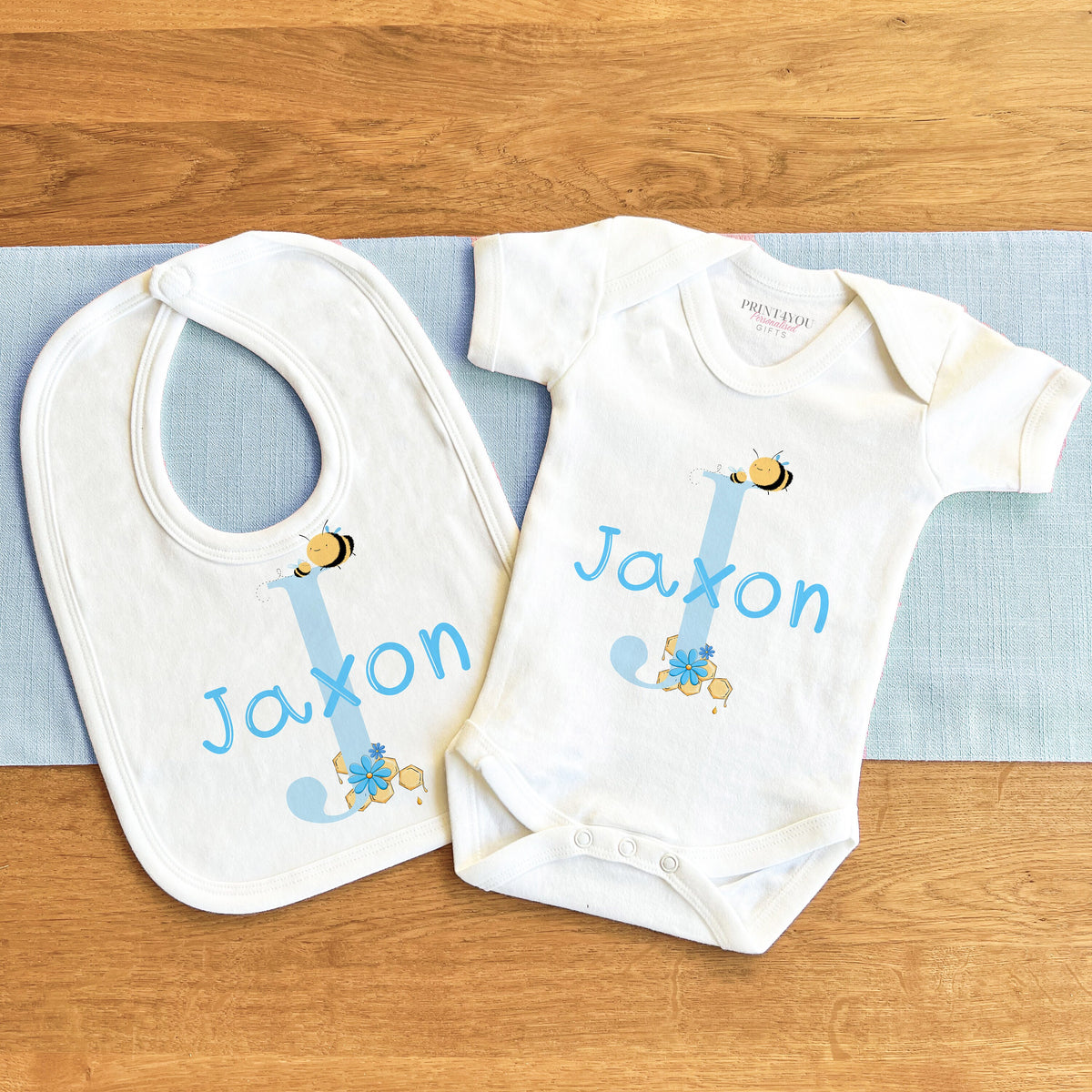 Personalised blue alphabet bumblebee bodysuit with baby's name printed on the front in soft cotton.