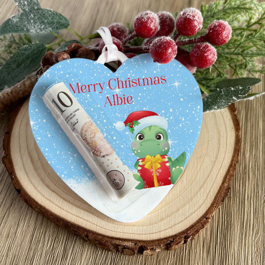 Clear acrylic heart-shaped Christmas money holder with a dinosaur design and personalised name, ribbon attached for hanging