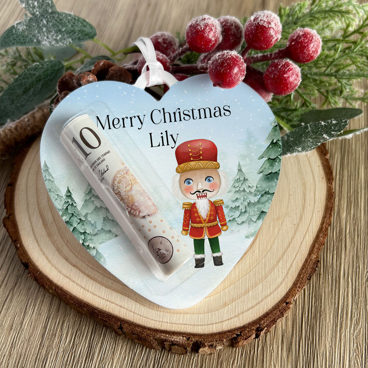Clear acrylic heart-shaped Christmas money holder with a nutcracker soldier design and personalised name, ribbon attached for hanging