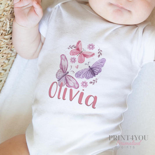 Personalised new baby bib in white cotton printed with pink and purple butterflies and the baby's name.