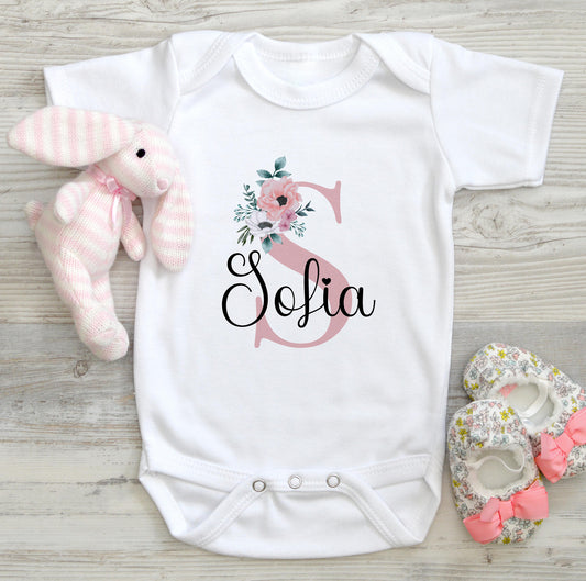 White cotton baby bib printed with pink florals, an initial letter and baby's name.