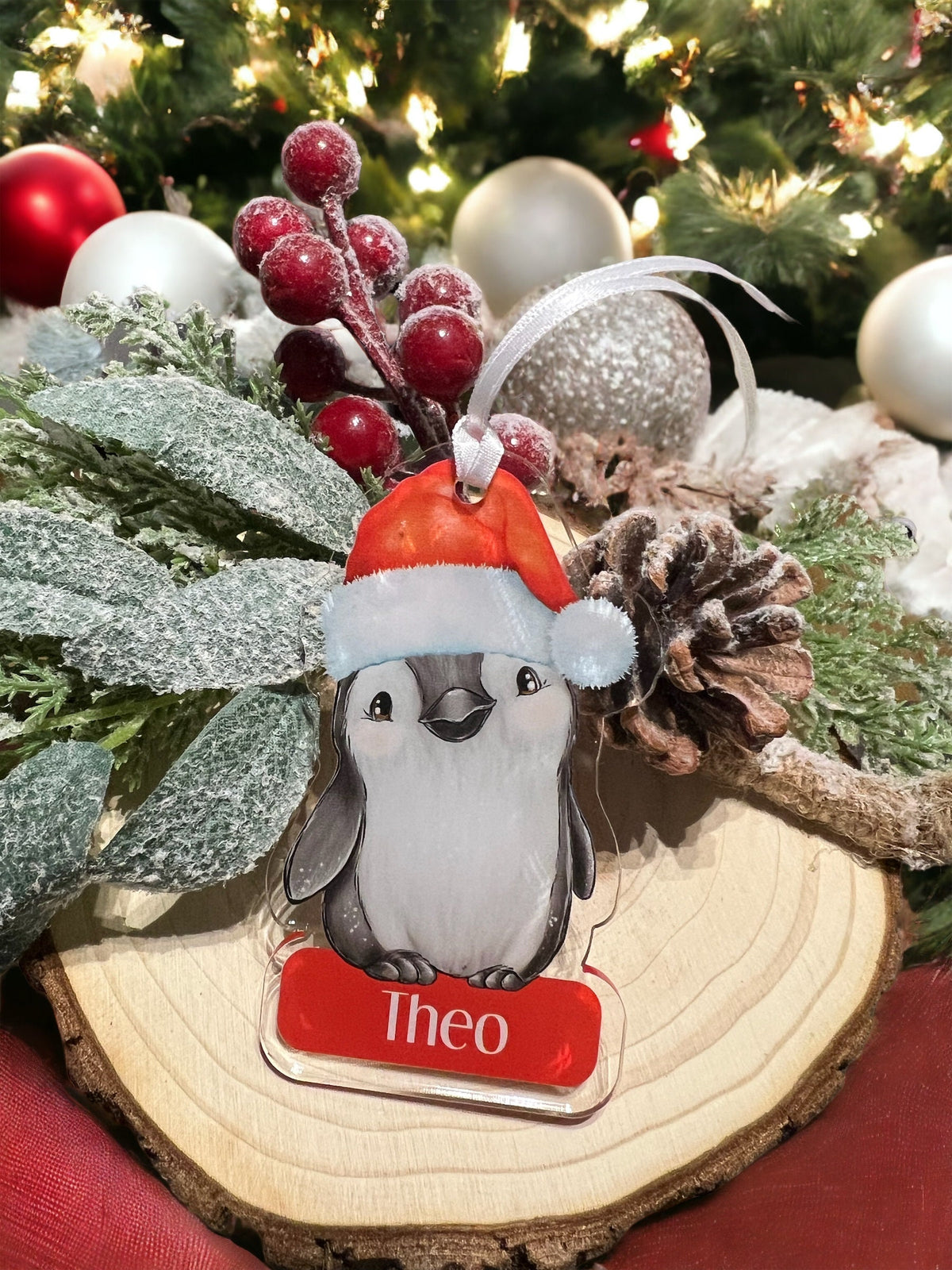 Personalised Penguin acrylic bauble hanging on a Christmas tree branch