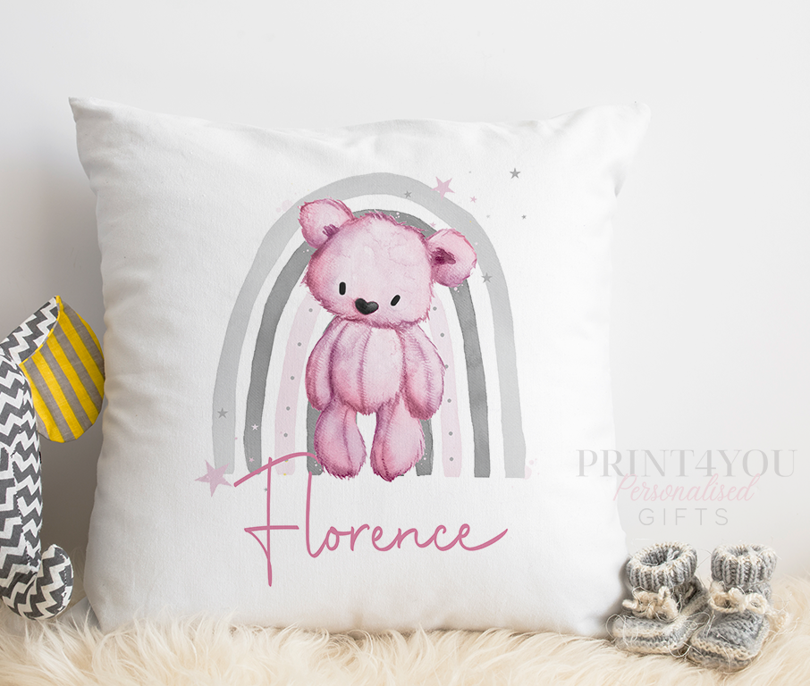 Close-up of a white nursery cushion printed with a pink teddy bear and grey rainbow design, personalised with the name Florence.